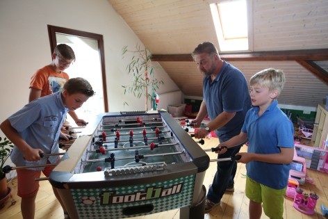 Drei Kinder und ein Erzieher am Kickertisch