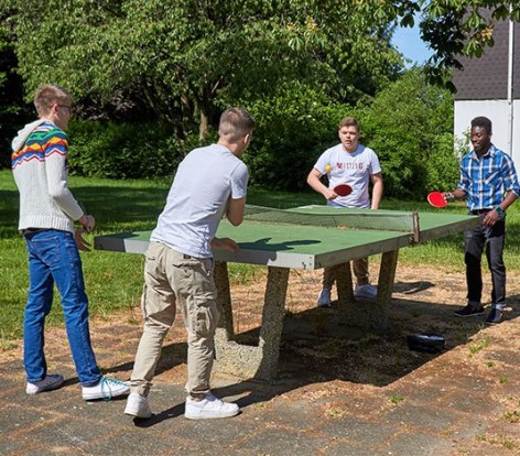 Vier Jugendliche spielen Tischtennis zusammen