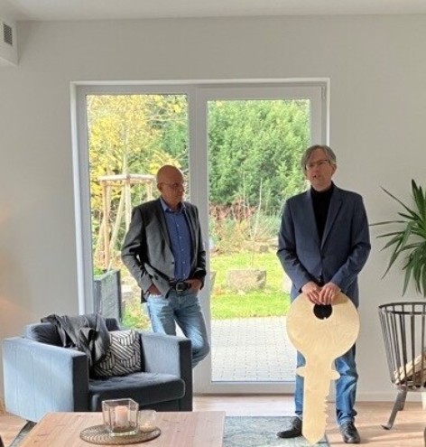 Zwei Herren übergeben einen symbolischen Holzschlüssel